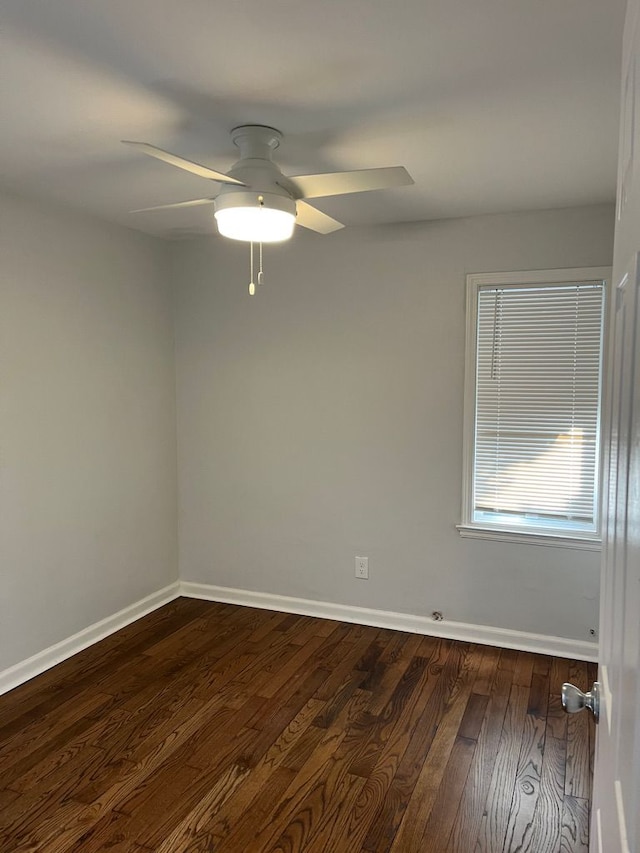 spare room featuring baseboards, dark wood finished floors, and a ceiling fan