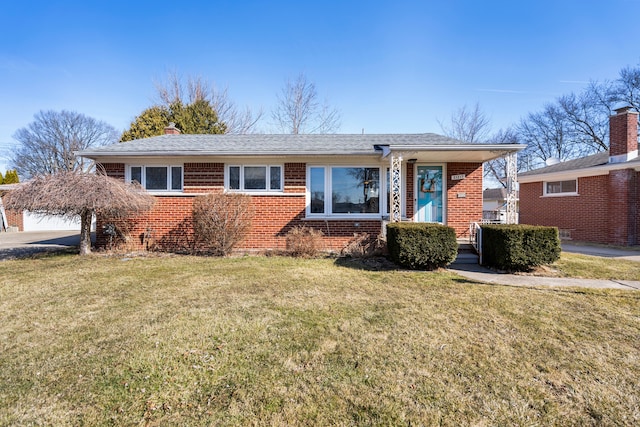 view of front of property with a front lawn, brick siding, driveway, and a chimney