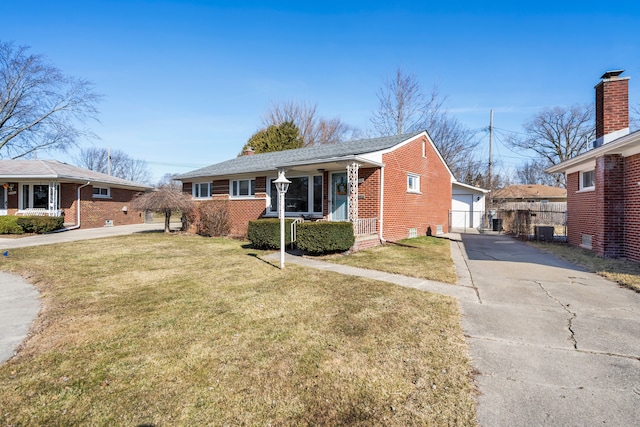 view of front of house featuring a front yard, fence, brick siding, and a detached garage