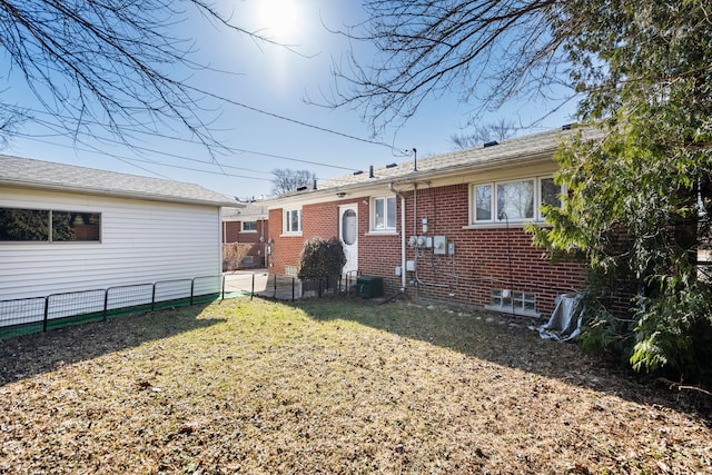 back of property with brick siding, a lawn, cooling unit, and fence