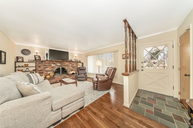 living area with dark wood-type flooring, a brick fireplace, baseboards, and ornamental molding