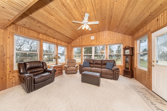 living area with vaulted ceiling, wood walls, a healthy amount of sunlight, and carpet floors