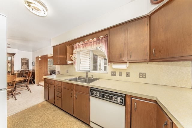 kitchen featuring a sink, brown cabinets, light countertops, and white dishwasher