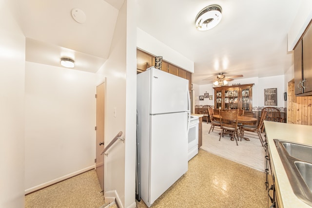 kitchen featuring brown cabinets, a sink, white appliances, light countertops, and ceiling fan