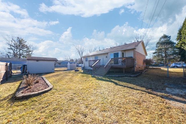 rear view of house featuring a wooden deck, a fenced backyard, an outdoor structure, a storage shed, and a lawn