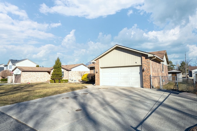 view of front of house featuring driveway, brick siding, an attached garage, and a gate