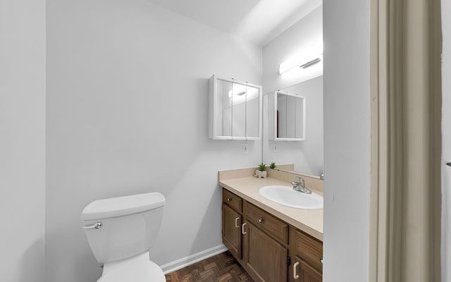 half bath with vanity, toilet, and baseboards