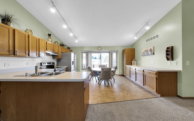 kitchen with under cabinet range hood, stainless steel appliances, a peninsula, light countertops, and vaulted ceiling