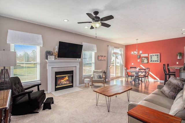 living room with a tiled fireplace, recessed lighting, ceiling fan with notable chandelier, and baseboards