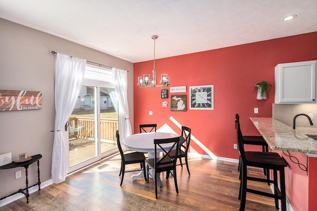 dining space with visible vents, baseboards, an inviting chandelier, and wood finished floors