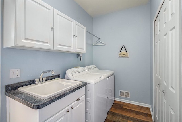 clothes washing area featuring baseboards, cabinet space, a sink, dark wood-type flooring, and washer and dryer