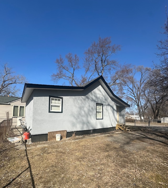 view of side of property featuring fence and stucco siding