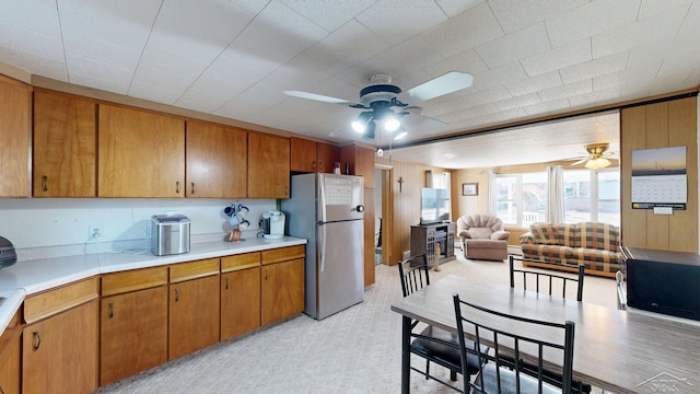 kitchen with light countertops, open floor plan, brown cabinets, and freestanding refrigerator