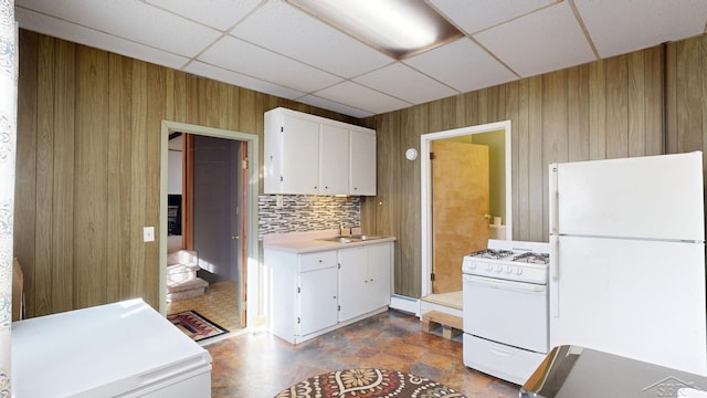 kitchen featuring white appliances, wooden walls, light countertops, and white cabinets