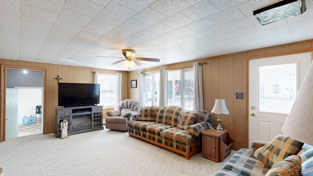 carpeted living room featuring wood walls and a ceiling fan