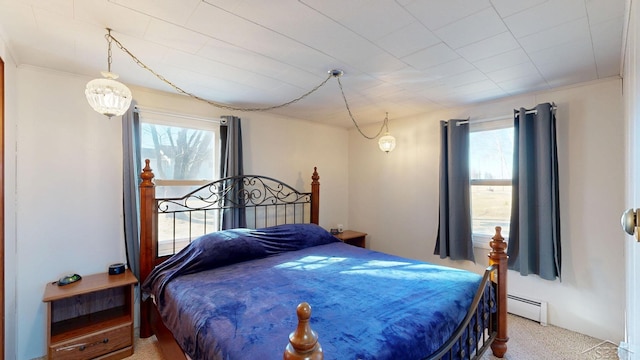 carpeted bedroom featuring multiple windows and a baseboard radiator