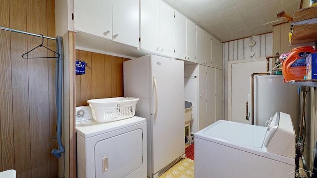 laundry room with wooden walls, cabinet space, independent washer and dryer, and water heater