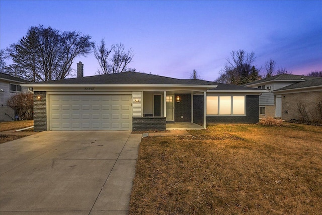 ranch-style house featuring a chimney, concrete driveway, a garage, a lawn, and brick siding