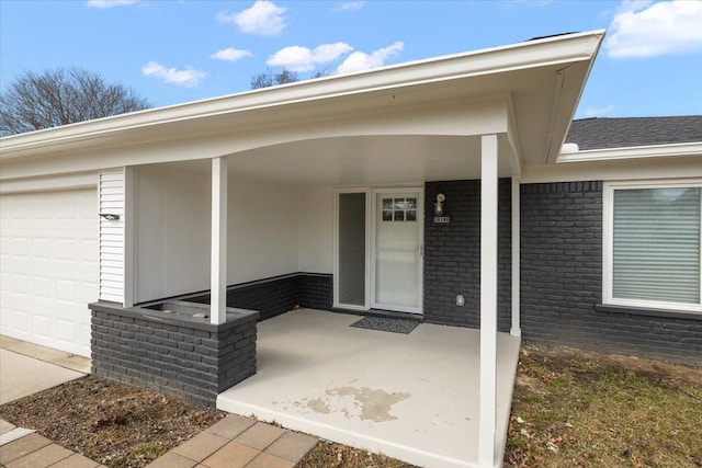 entrance to property with an attached garage, covered porch, and brick siding