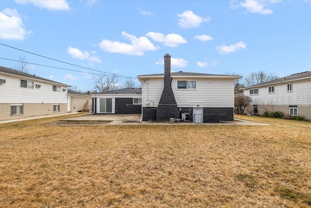 rear view of house featuring a patio area, a lawn, and a chimney