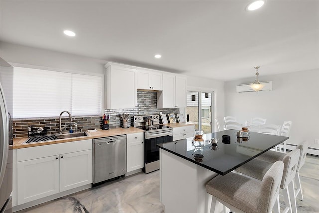 kitchen featuring a sink, backsplash, white cabinetry, appliances with stainless steel finishes, and a breakfast bar area