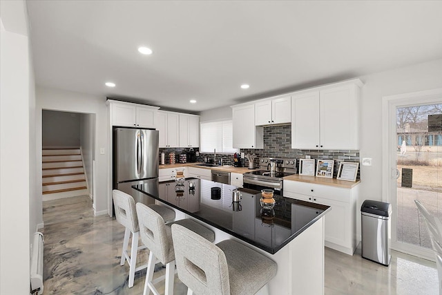 kitchen featuring decorative backsplash, a kitchen bar, white cabinetry, and appliances with stainless steel finishes