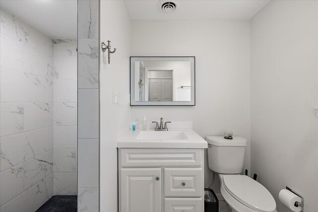 full bathroom featuring visible vents, toilet, vanity, and tiled shower