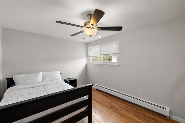 bedroom featuring baseboard heating, wood finished floors, and a ceiling fan