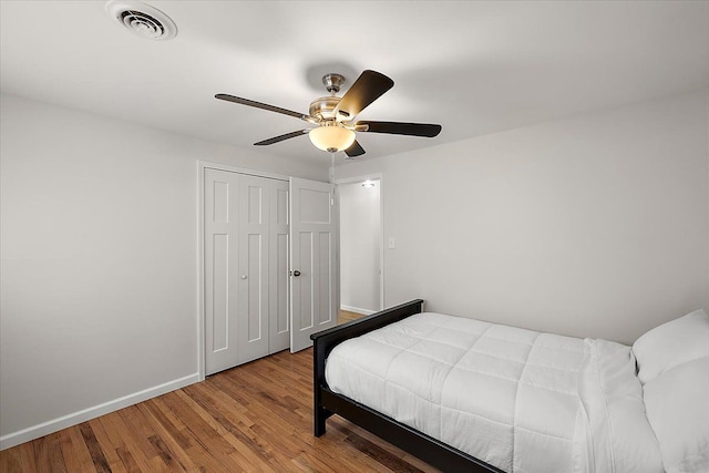 bedroom with visible vents, wood finished floors, a closet, baseboards, and ceiling fan