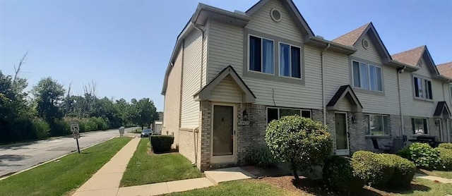 view of front facade with brick siding and a front lawn