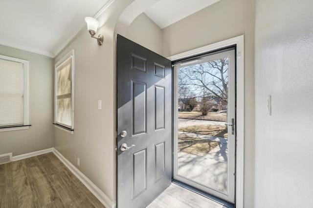 entryway featuring wood finished floors, baseboards, and arched walkways