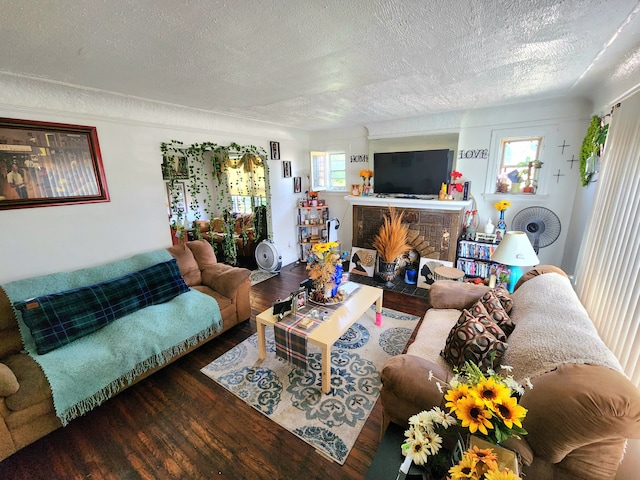 living area featuring a brick fireplace, a textured ceiling, and wood finished floors