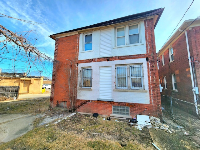 rear view of property featuring fence and brick siding