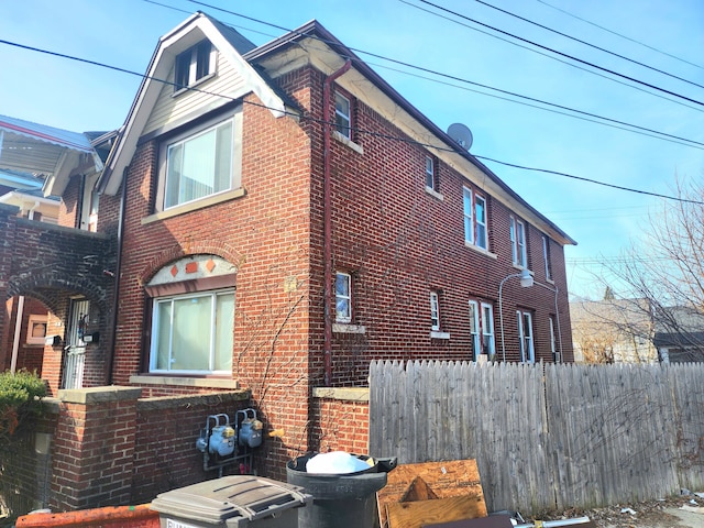 view of home's exterior featuring brick siding and fence