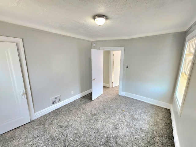 unfurnished bedroom with baseboards, carpet flooring, a textured ceiling, and visible vents