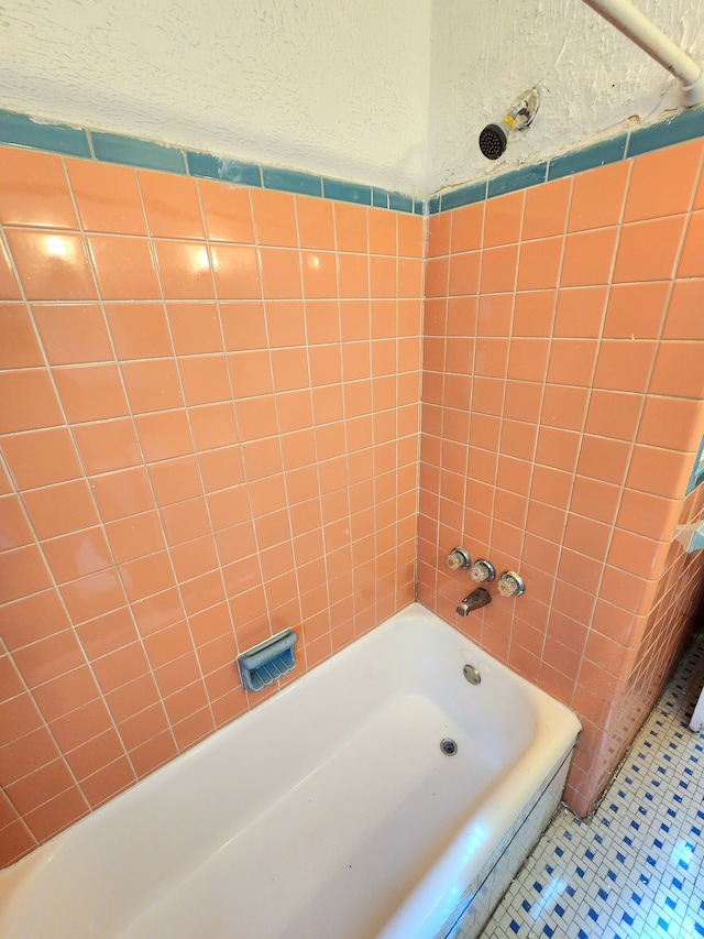 bathroom with a textured wall, shower / bathing tub combination, and tile patterned flooring