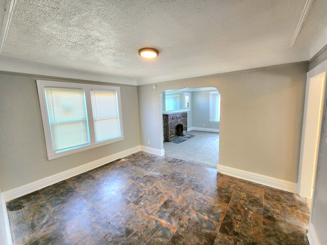 unfurnished living room with plenty of natural light, baseboards, arched walkways, and a fireplace with flush hearth