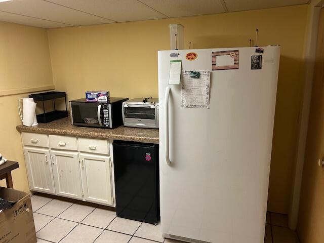 kitchen with a toaster, refrigerator, freestanding refrigerator, and a drop ceiling