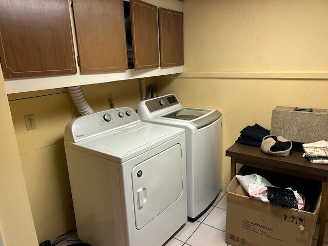 laundry room featuring light tile patterned floors, cabinet space, and independent washer and dryer