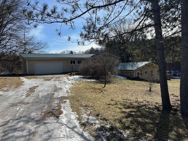 view of front of house with driveway, metal roof, and a garage