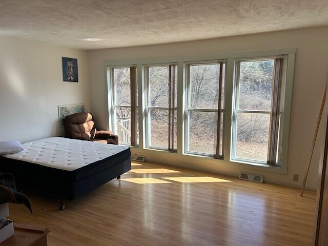 bedroom featuring visible vents, a textured ceiling, and wood finished floors