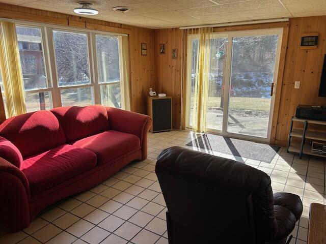 living area featuring a wealth of natural light, wood walls, and light tile patterned flooring