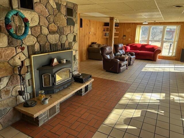 living area featuring wooden walls, a wood stove, and visible vents