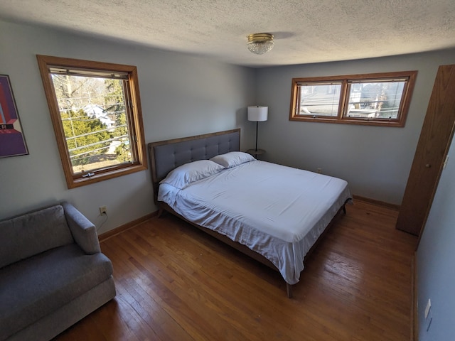 bedroom featuring a textured ceiling, baseboards, and wood-type flooring