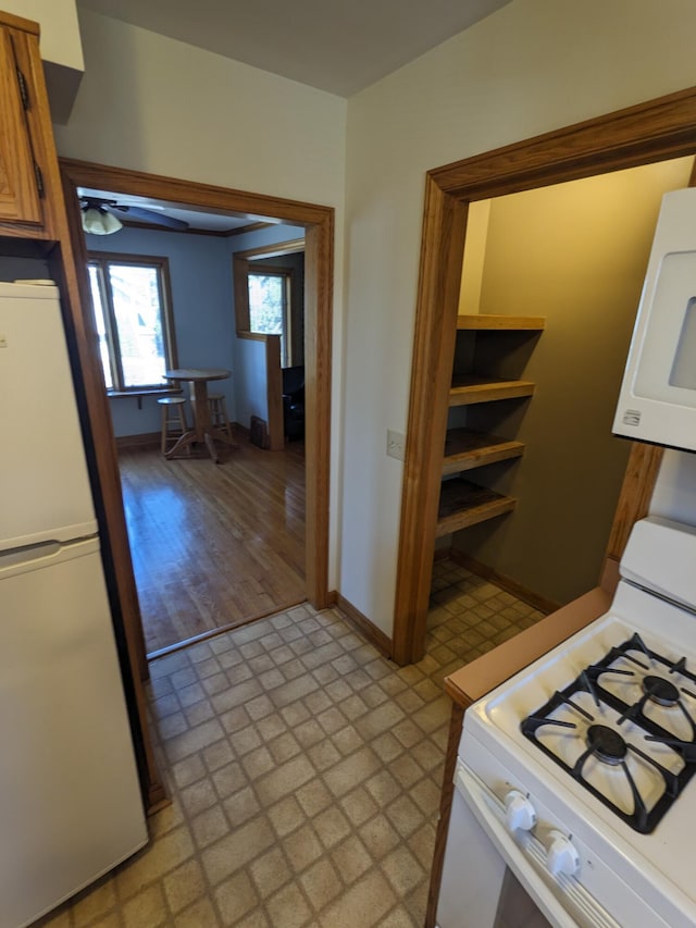 kitchen with white appliances, brown cabinetry, and baseboards