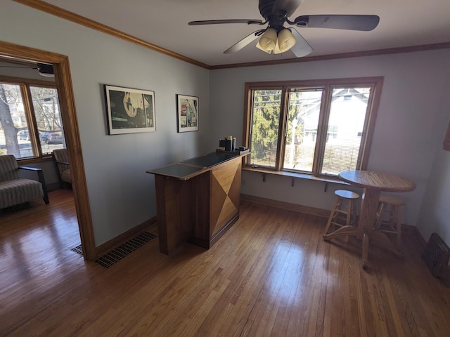 office area with hardwood / wood-style floors, baseboards, visible vents, ceiling fan, and ornamental molding