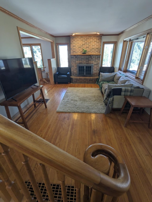 living area featuring crown molding, a brick fireplace, and wood-type flooring