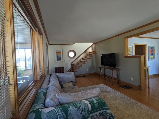 living area with wood finished floors, stairs, and ornamental molding