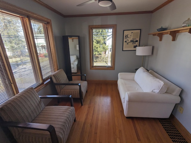 living room featuring plenty of natural light, wood finished floors, baseboards, and ornamental molding