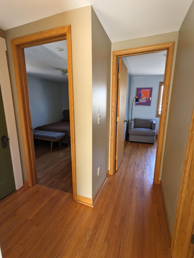 hall with baseboards and wood-type flooring